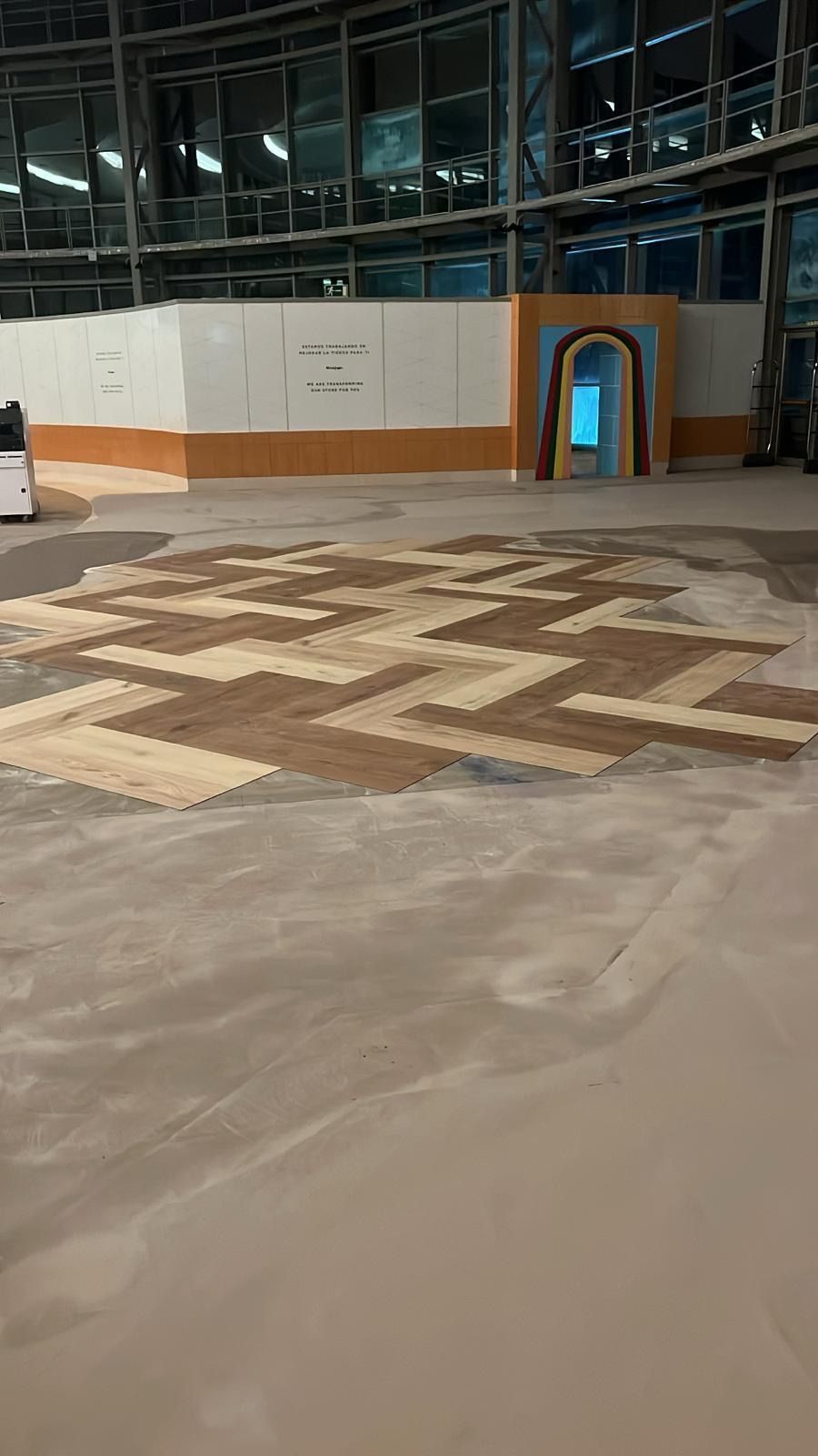 Obra interior en construcción con suelo estampado en tonos marrones y tostados, con paredes y arco.