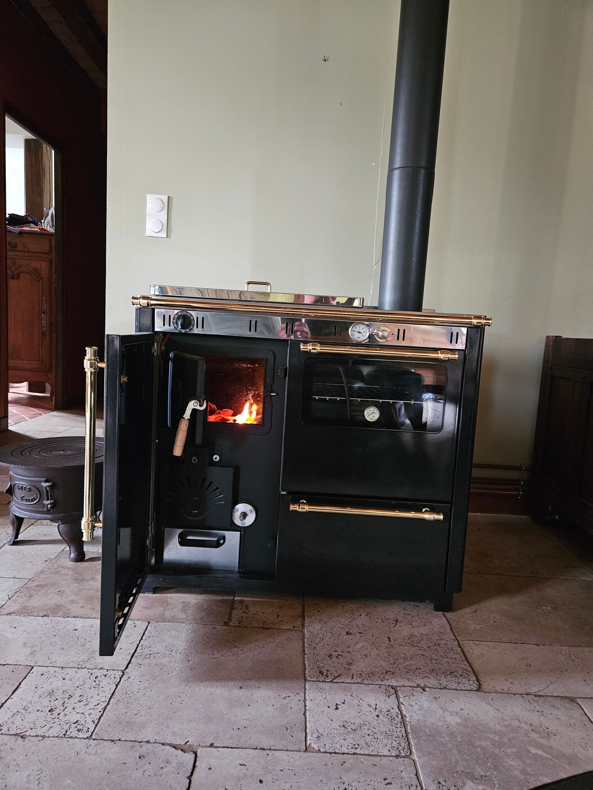 Cuisinière avec des flammes visibles à l'intérieur, posé sur un sol carrelé dans une pièce