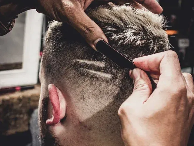 Un hombre se está cortando el pelo con una navaja por un barbero.