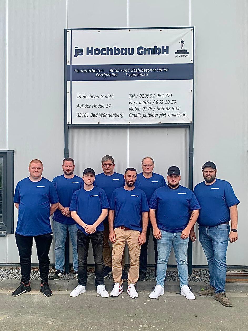 Eine Gruppe Männer posiert vor einem Gebäude für ein Foto.