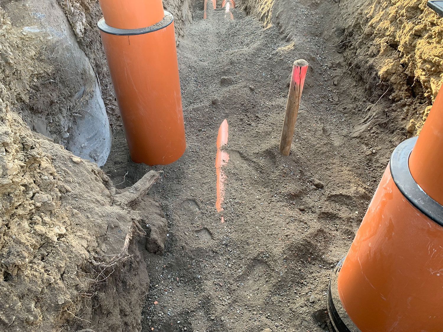 Ein Haufen orangefarbener Rohre liegt im Dreck.