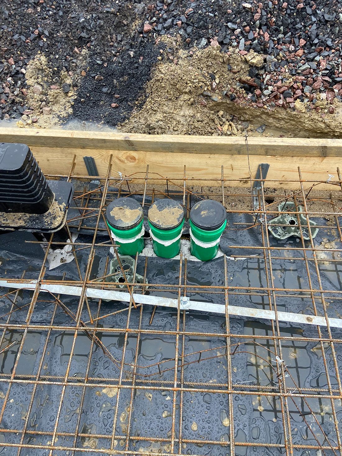 Drei grüne Eimer stehen auf einem Metallgitter.