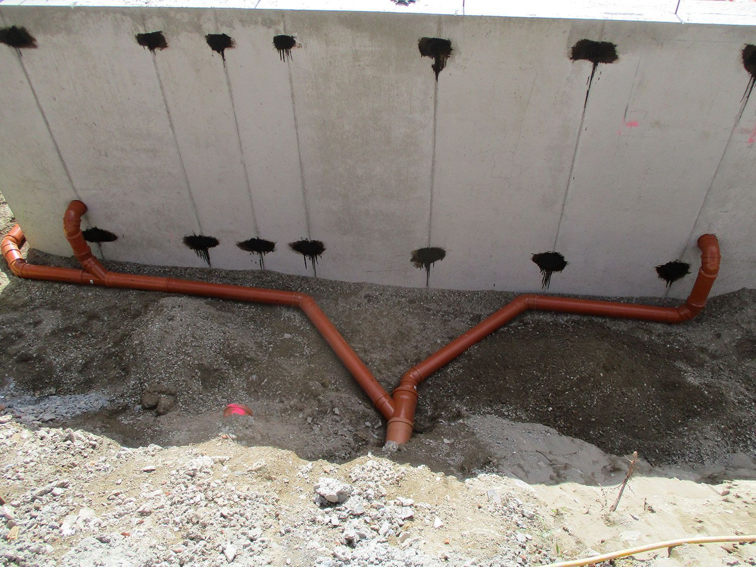 Eine Betonwand, aus der ein Haufen Rohre herausragen