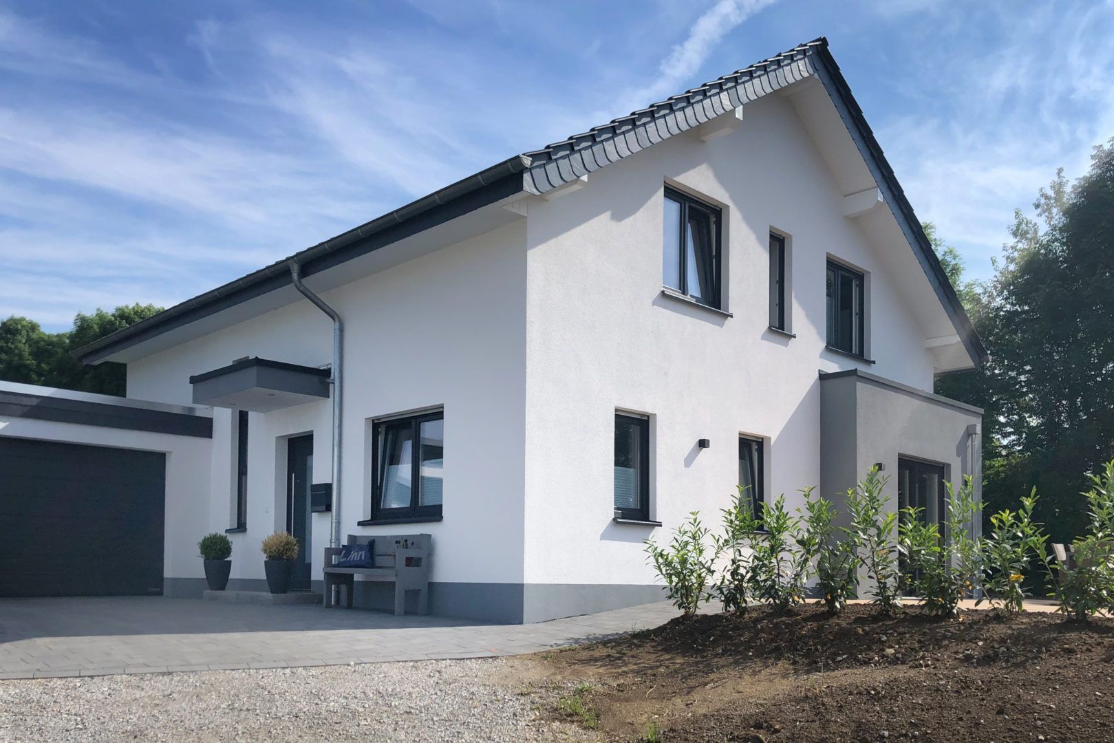 Ein weißes Haus mit schwarzem Dach und einer Garage