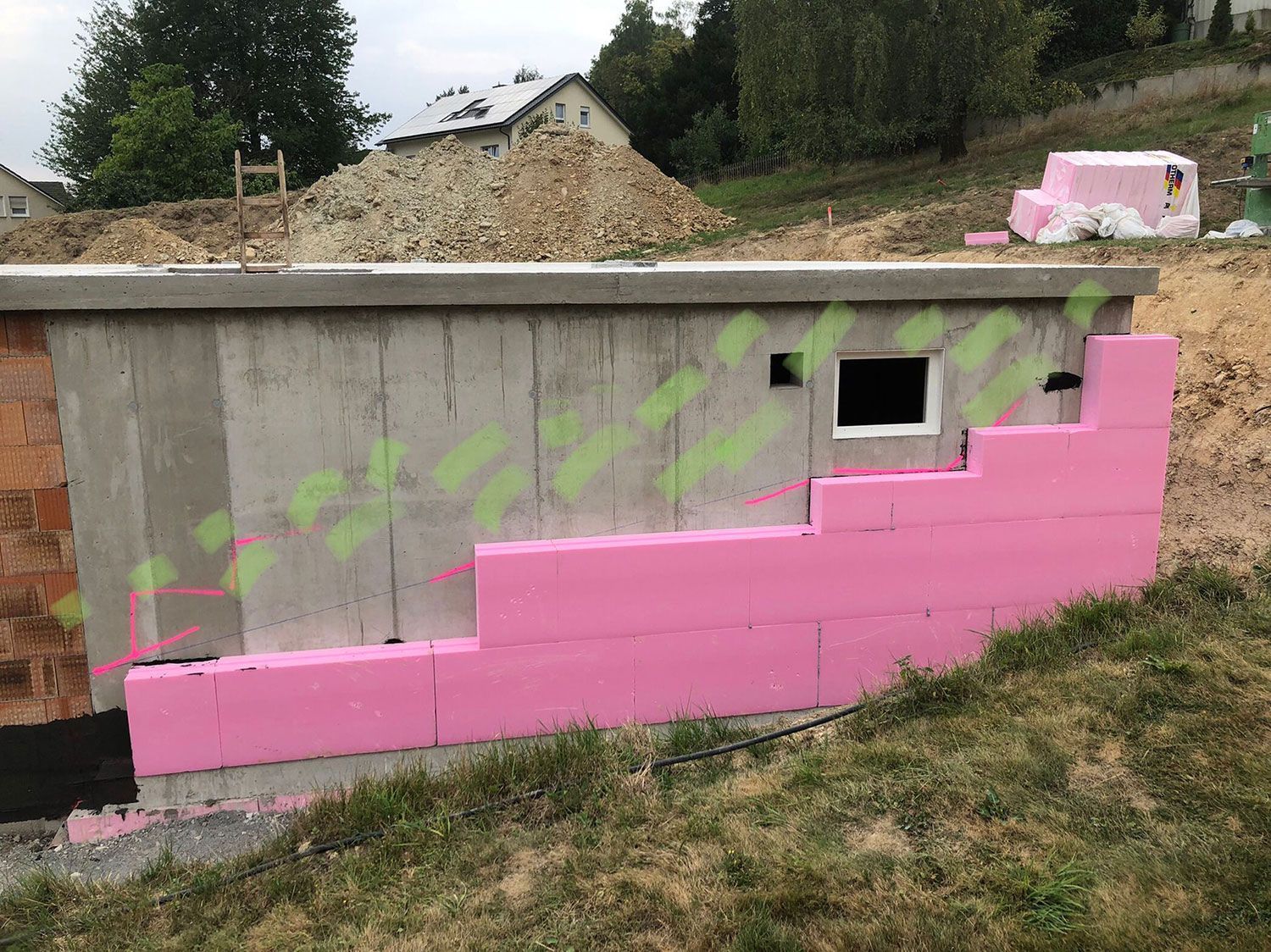 Es wird eine Betonwand mit rosafarbener Isolierung gebaut.