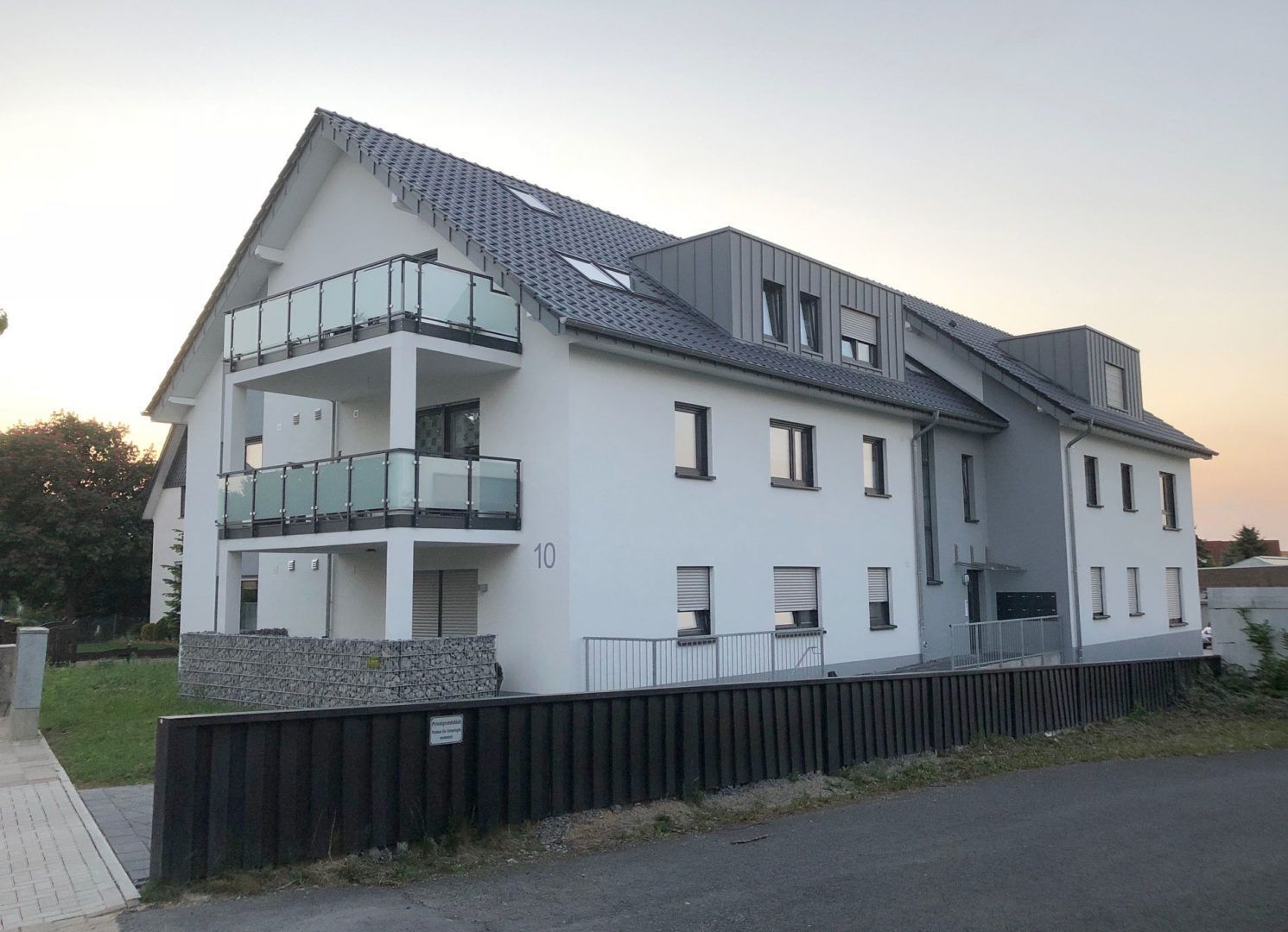 Ein großes weißes Gebäude mit Balkonen und einem schwarzen Zaun