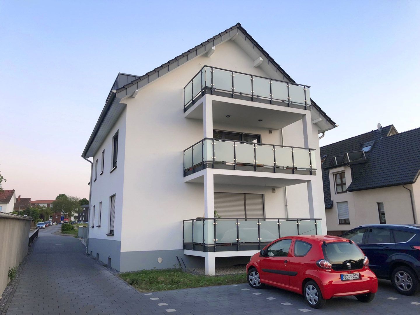 Ein rotes Auto steht vor einem Gebäude mit Balkonen