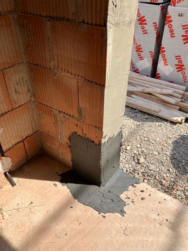 Eine Backsteinmauer mit einem Betonpfeiler in der Mitte.