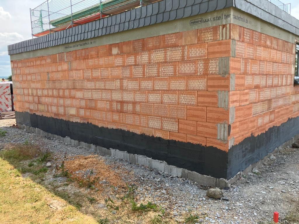 Auf einer Baustelle wird eine Ziegelmauer gebaut.