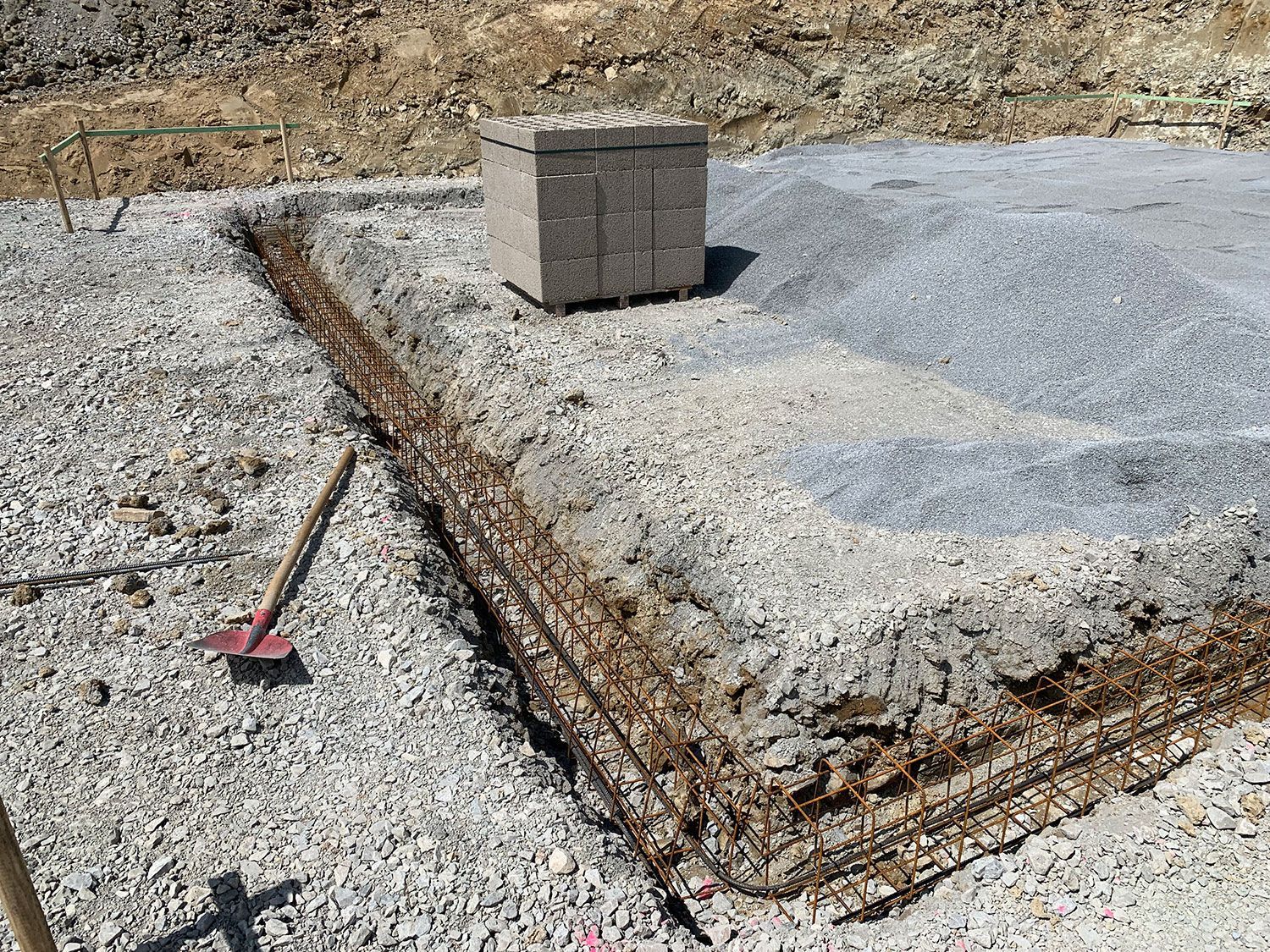 Ein Betonblock liegt neben einem Besen auf einem Kieshaufen.