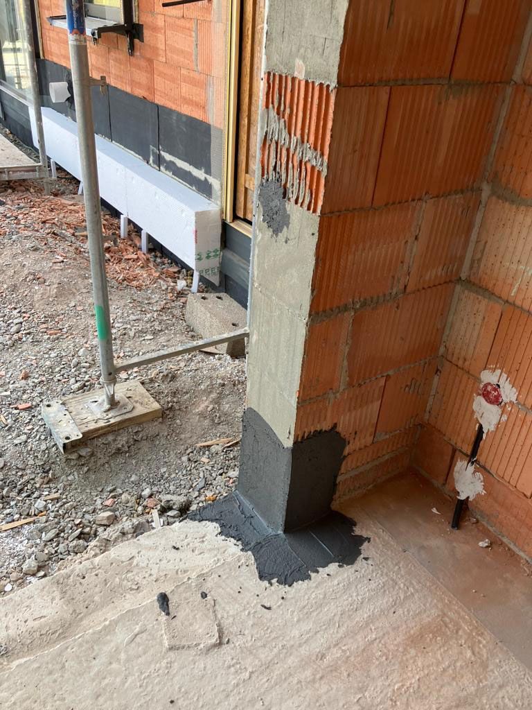 Eine Backsteinmauer mit einem Betonpfeiler in der Mitte.