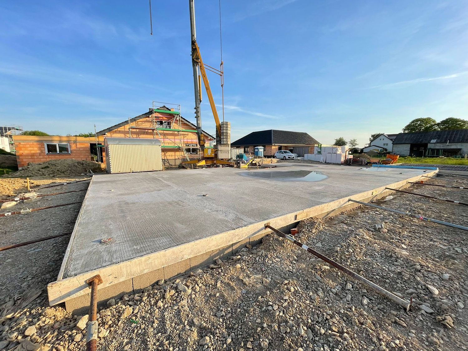 Ein Kran hebt auf einer Baustelle eine Betonplatte an.