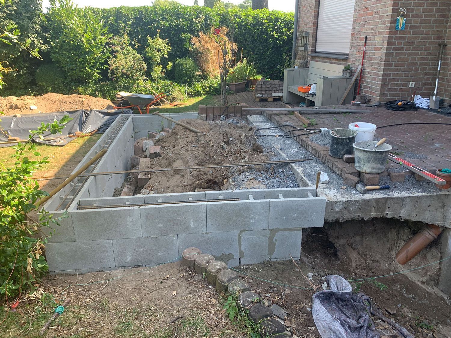 Im Hinterhof eines Hauses wird eine Ziegelmauer gebaut.