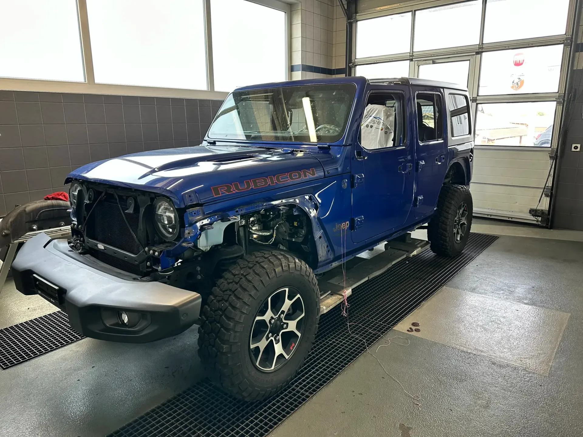 Ein blauer Jeep Wrangler steht in einer Garage.