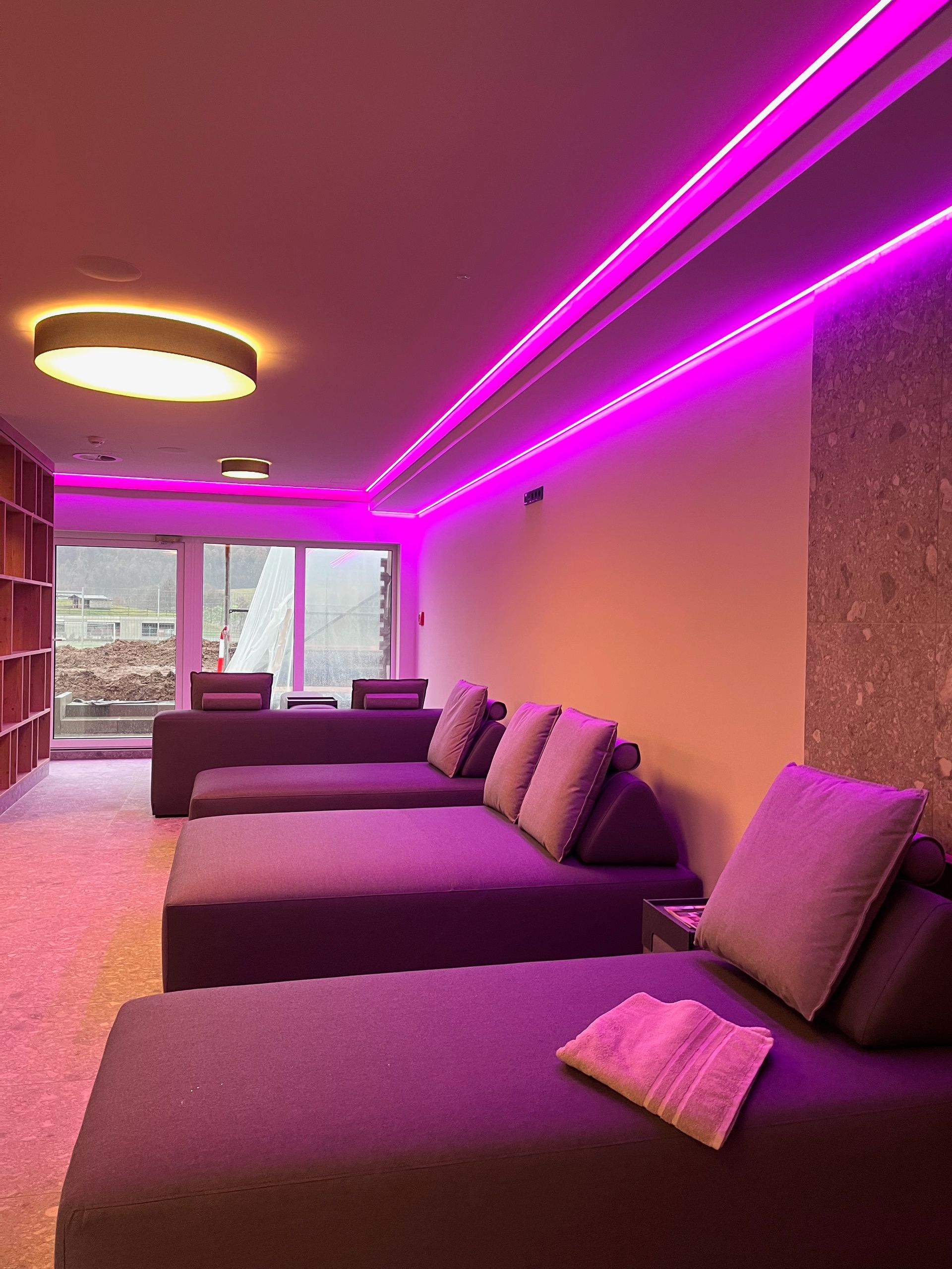 Ein großer Ruheraum mit Liegen und violetten Lichtern.