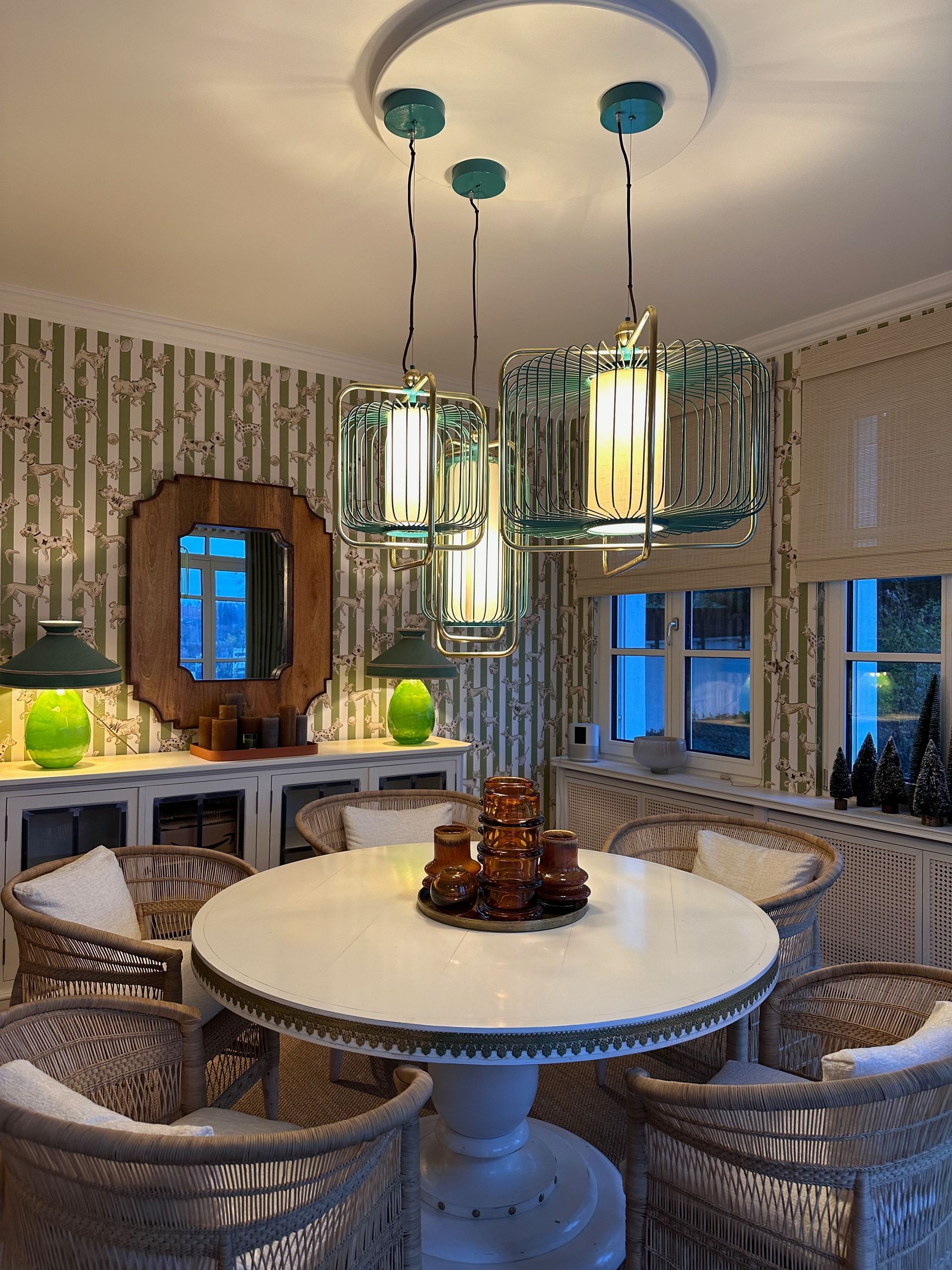 Ein Esszimmer mit einem runden Tisch und Stühlen und einem Kronleuchter, der von der Decke hängt.