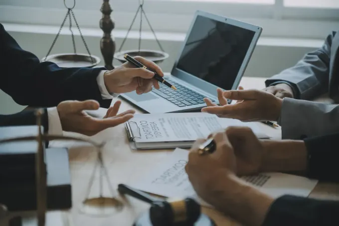 Abogados revisando documentos en una mesa con una computadora portátil, una balanza de justicia y un mazo.
