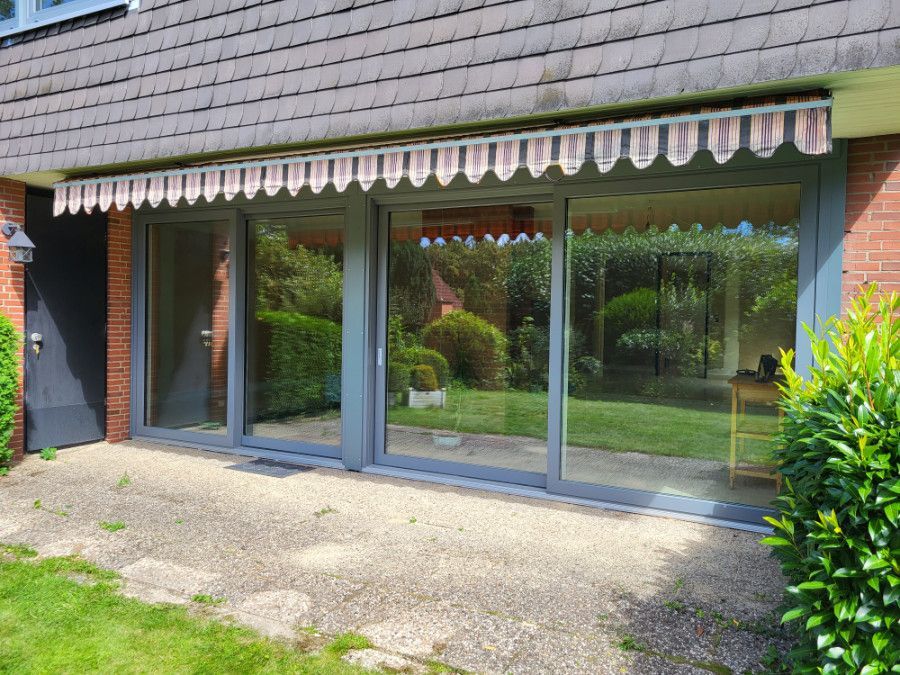 ein Haus mit Schiebetüren und einem weißen Sonnenschirm .