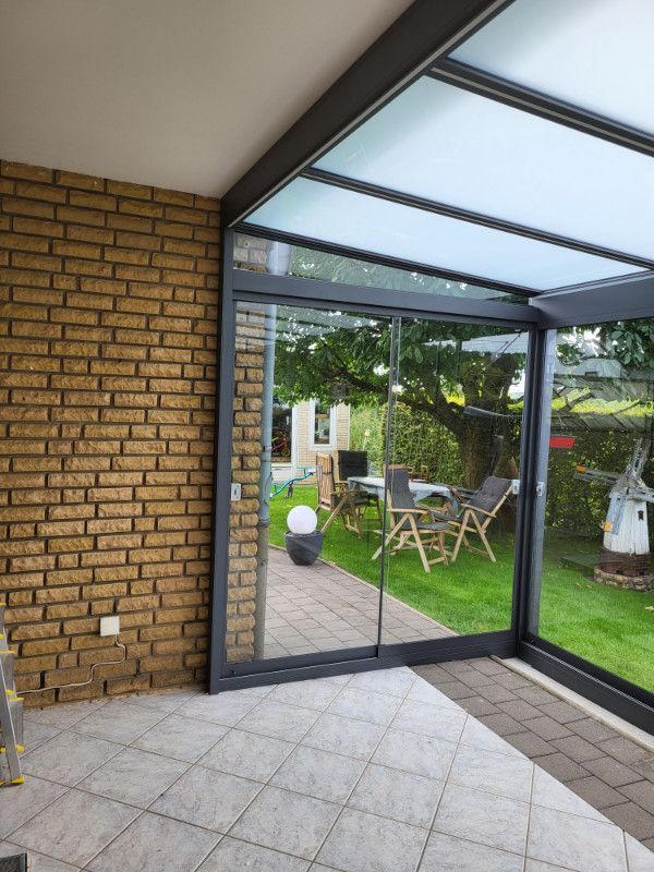 ein Raum mit einer Backsteinmauer und einer Schiebetür , die in einen Garten führt .