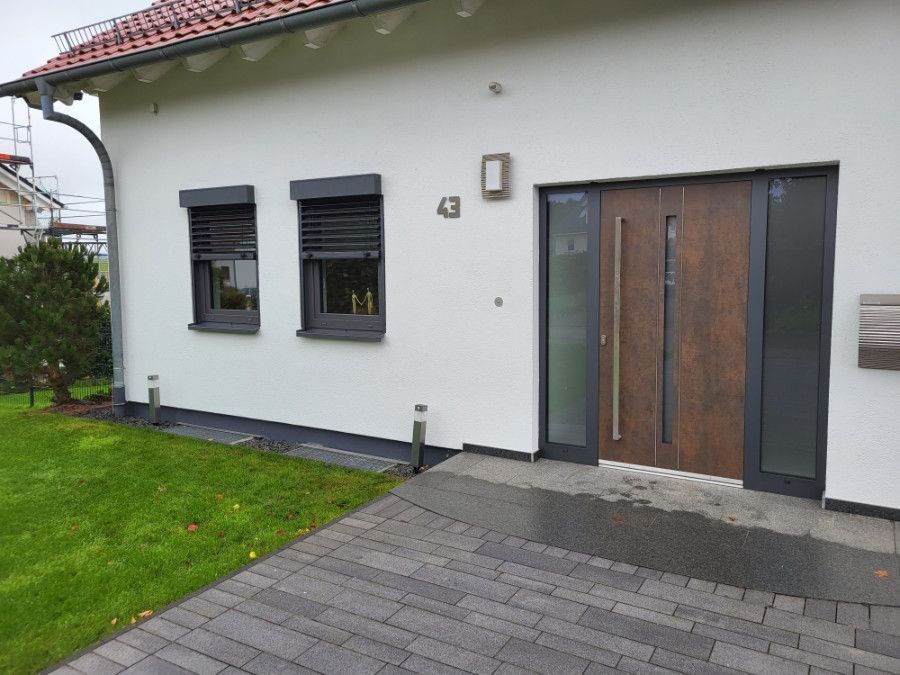 ein weißes Haus mit einer Holztür und zwei Fenstern .