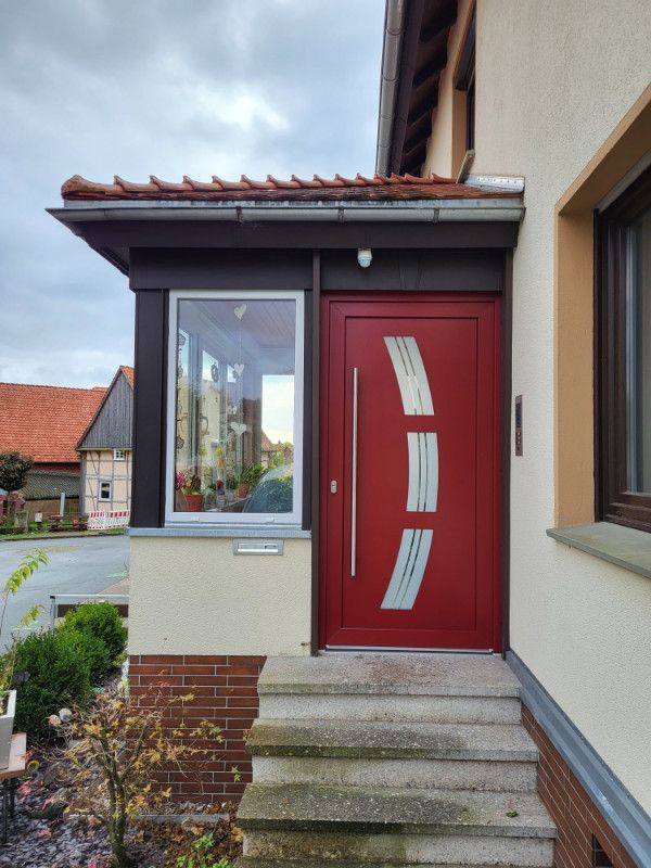 eine rote Haustür mit einem Fenster und einer Treppe