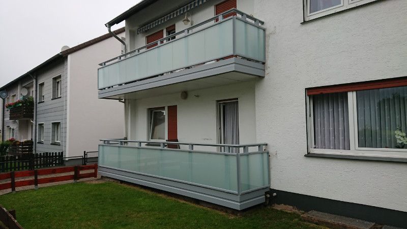 ein weißes Haus mit einem Balkon und vielen Fenstern .