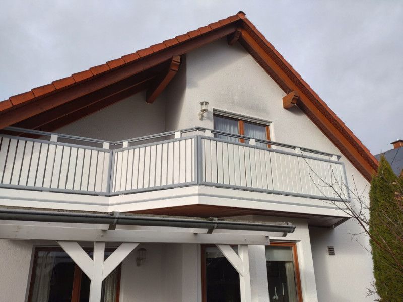 ein weißes Haus mit einem Balkon und einem roten Dach