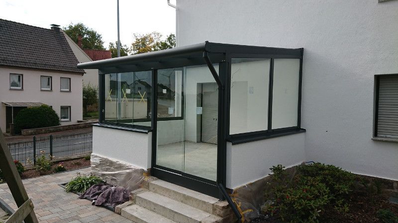 ein weißes Haus mit einer Veranda mit Glastüren .