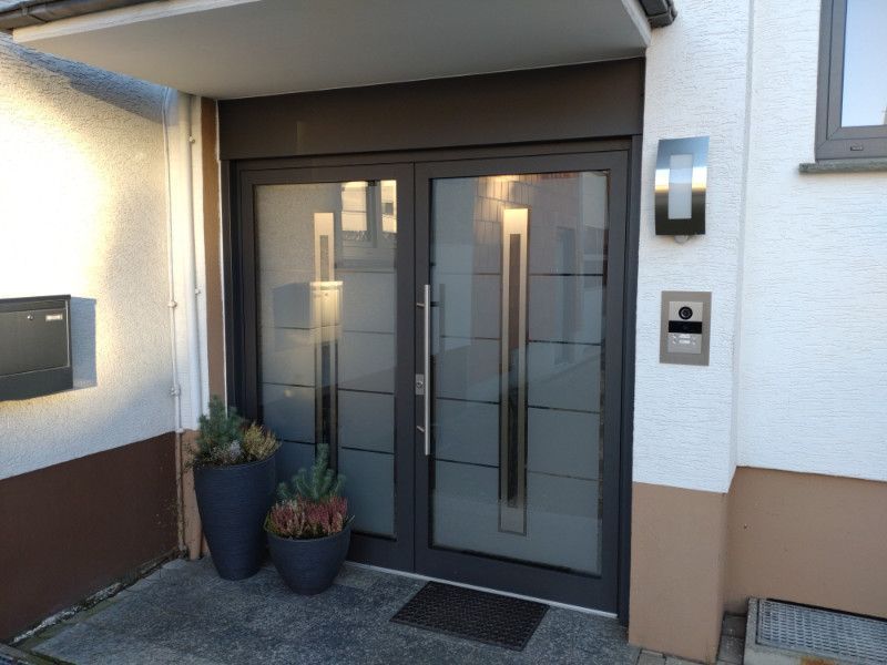 ein Haus mit einer großen Eingangstür und zwei Blumentöpfen davor