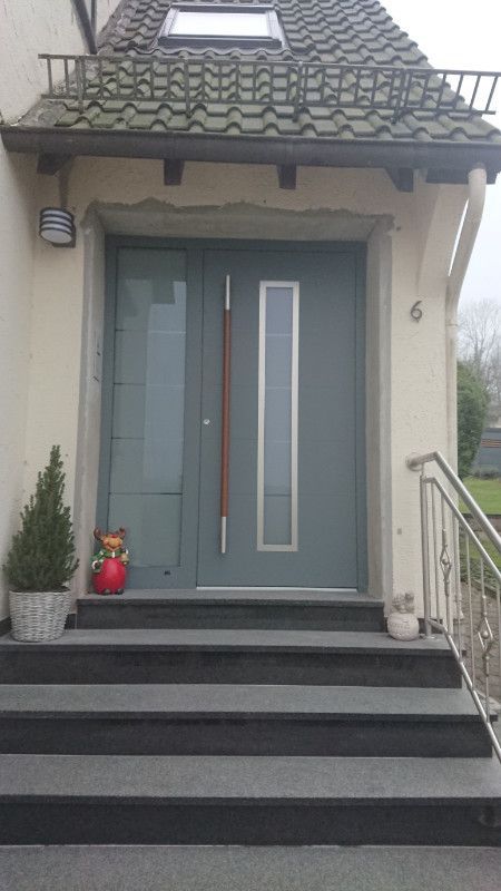 eine graue Haustür mit einem Dachfenster und einer Treppe .