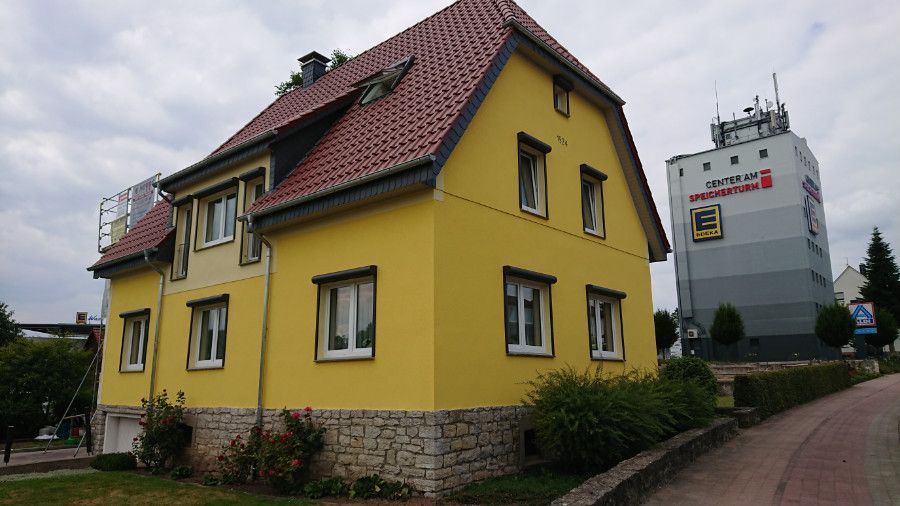 ein gelbes Haus mit einem roten Dach und vielen Fenstern