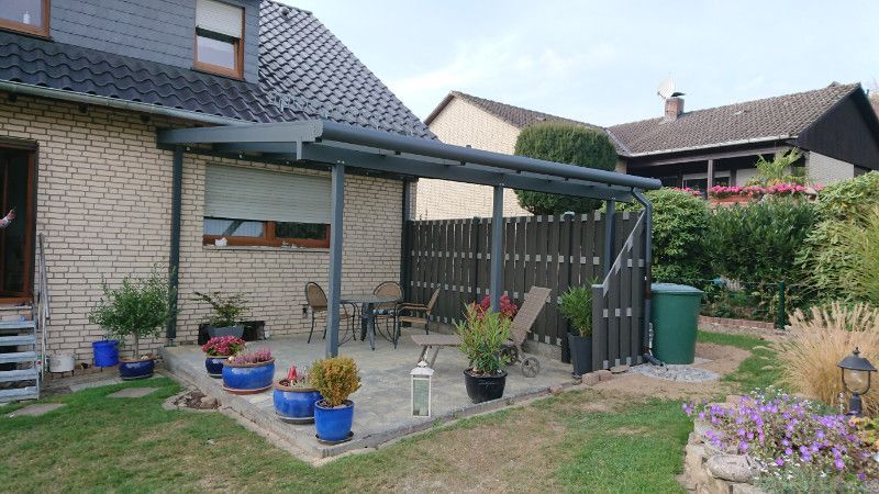 ein Backsteinhaus mit einer Veranda und einem Zaun dahinter .