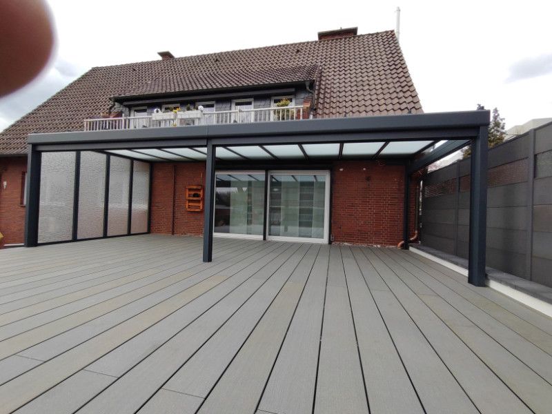 ein Deck mit einer Veranda und einem Backsteingebäude im Hintergrund