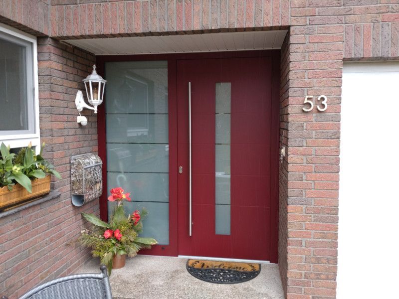 die Eingangstür eines Backsteinhauses mit einer roten Tür .