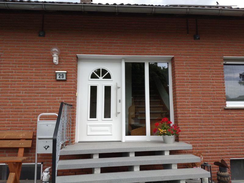 eine rote Backsteinmauer mit einer weißen Haustür und einer Treppe .