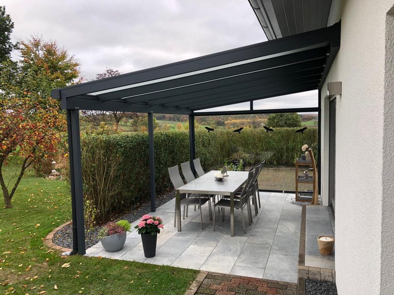 eine Veranda mit einem Tisch und Stühlen darauf .