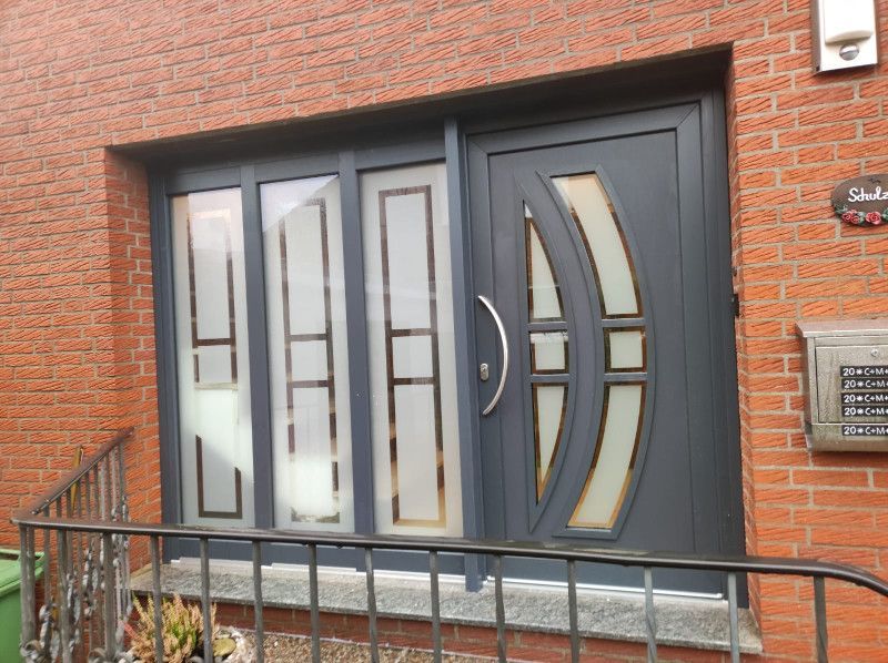 eine graue Haustür steht vor einem Backsteingebäude .