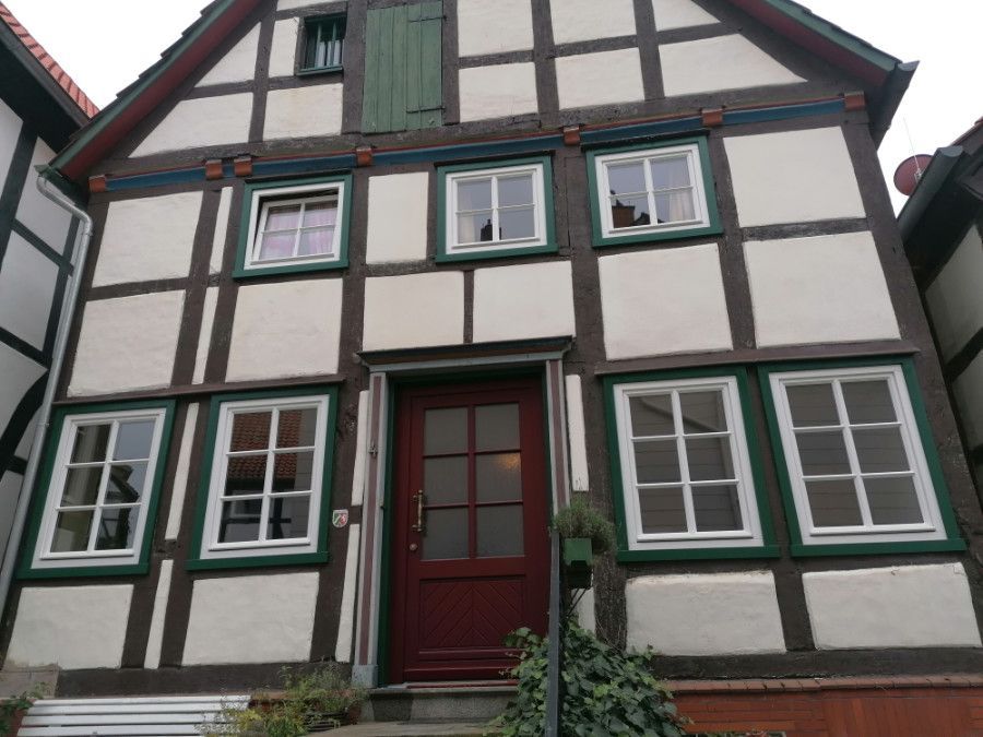 ein weiß-braunes Haus mit vielen Fenstern und einer roten Tür