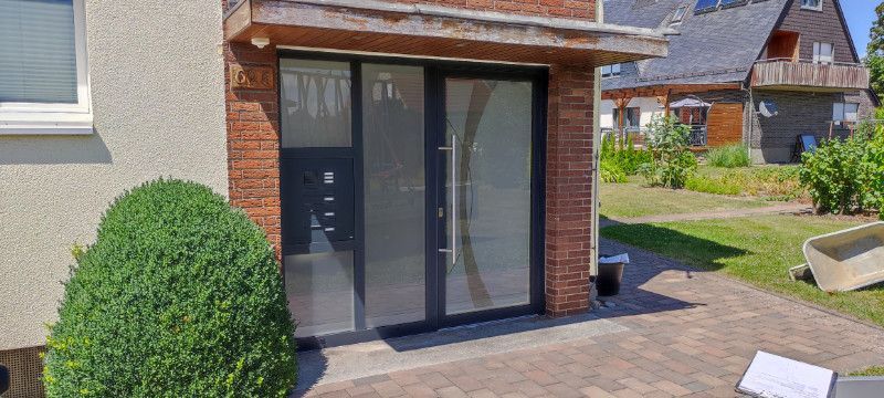 ein Haus mit einer schwarzen Eingangstür und einer roten Backsteinmauer .