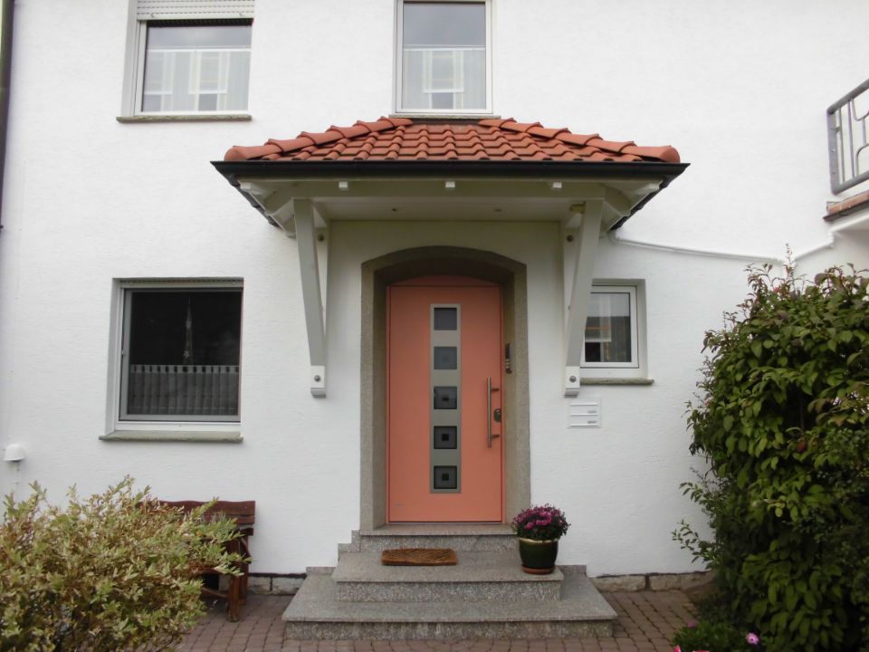 ein weißes Haus mit einer orangefarbenen Haustür