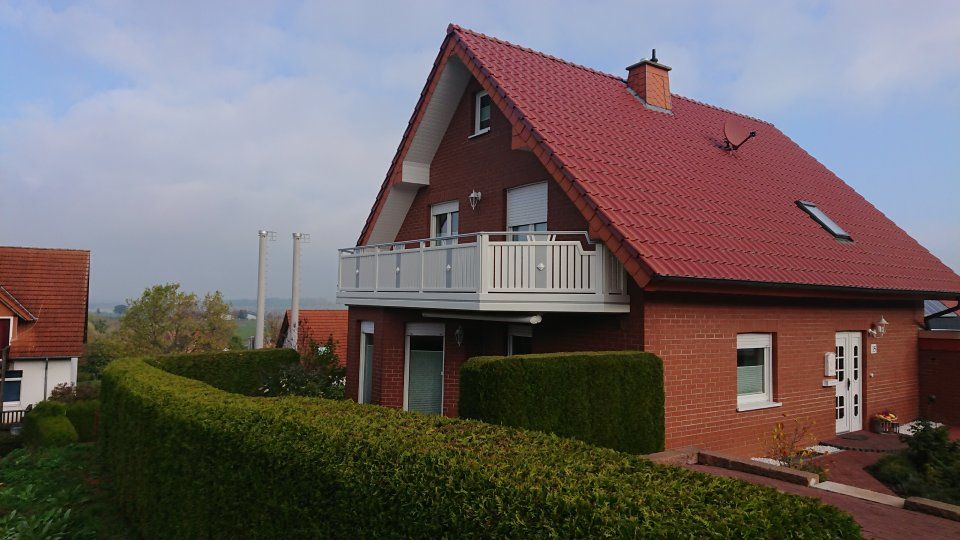 rotes Einfamilienhaus mit weißem Balkon