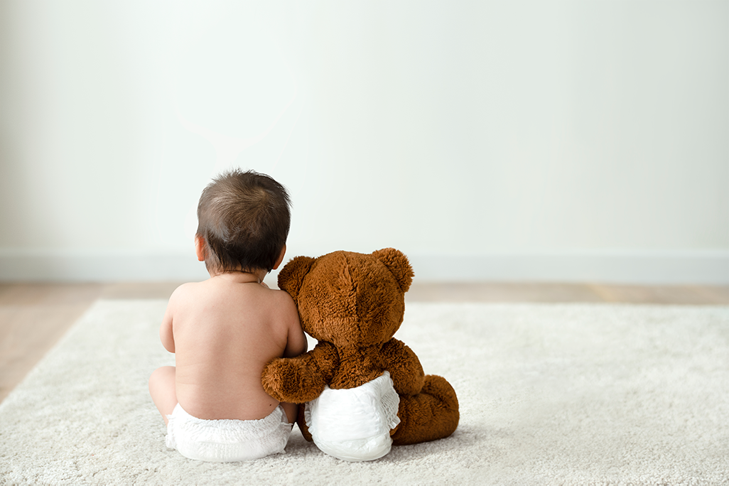 Un bébé et une peluche assis sur un tapis