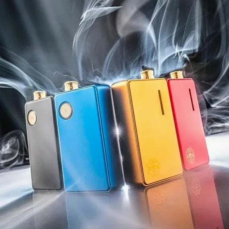 Cuatro dispositivos de vapeo de colores brillantes (plata, azul, dorado y rojo) sobre un fondo ahumado.