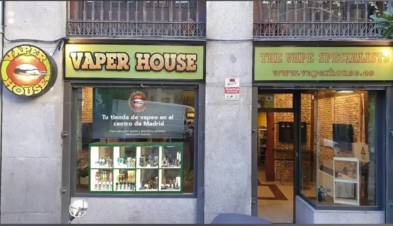 Escaparate de la tienda Vaper House con un cartel verde y amarillo que muestra productos de vapeo.