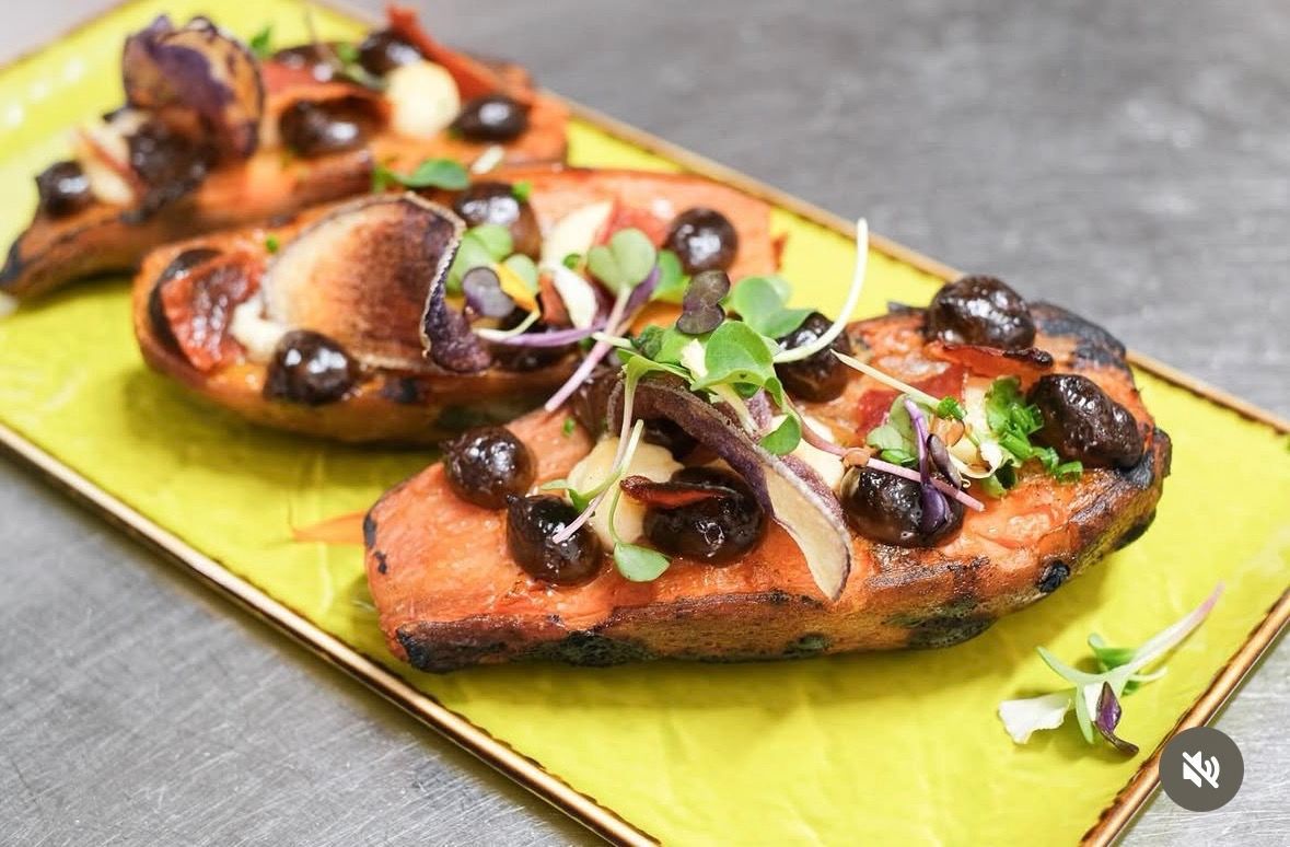 Tres rebanadas de bruschetta tostada cubiertas con champiñones, hierbas y glaseado balsámico en un plato verde.
