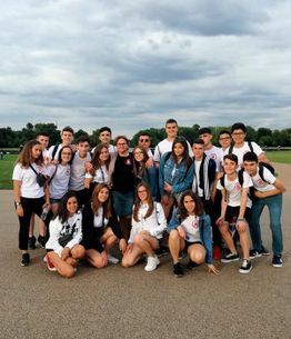 Grupo de personas posando juntas al aire libre en un día nublado, de pie y de rodillas sobre una zona pavimentada.