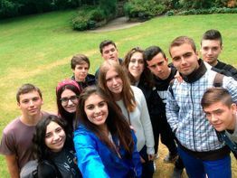 Un grupo de amigos posa al aire libre en una ladera cubierta de hierba, sonriendo a la cámara.