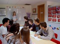 Alumnos sentados en un aula observando a un profesor hacer una presentación al frente de la sala.