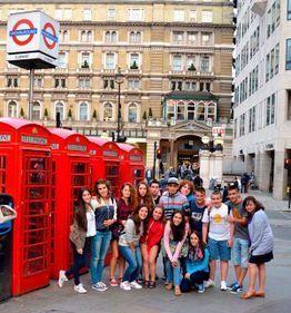 Grupo de personas posando junto a cabinas telefónicas rojas de Londres en una calle de la ciudad.