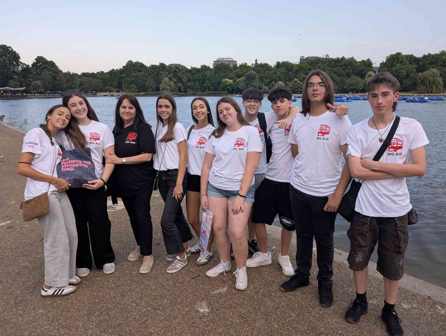 Grupo de personas con camisetas blancas posando al aire libre junto a un lago al atardecer.